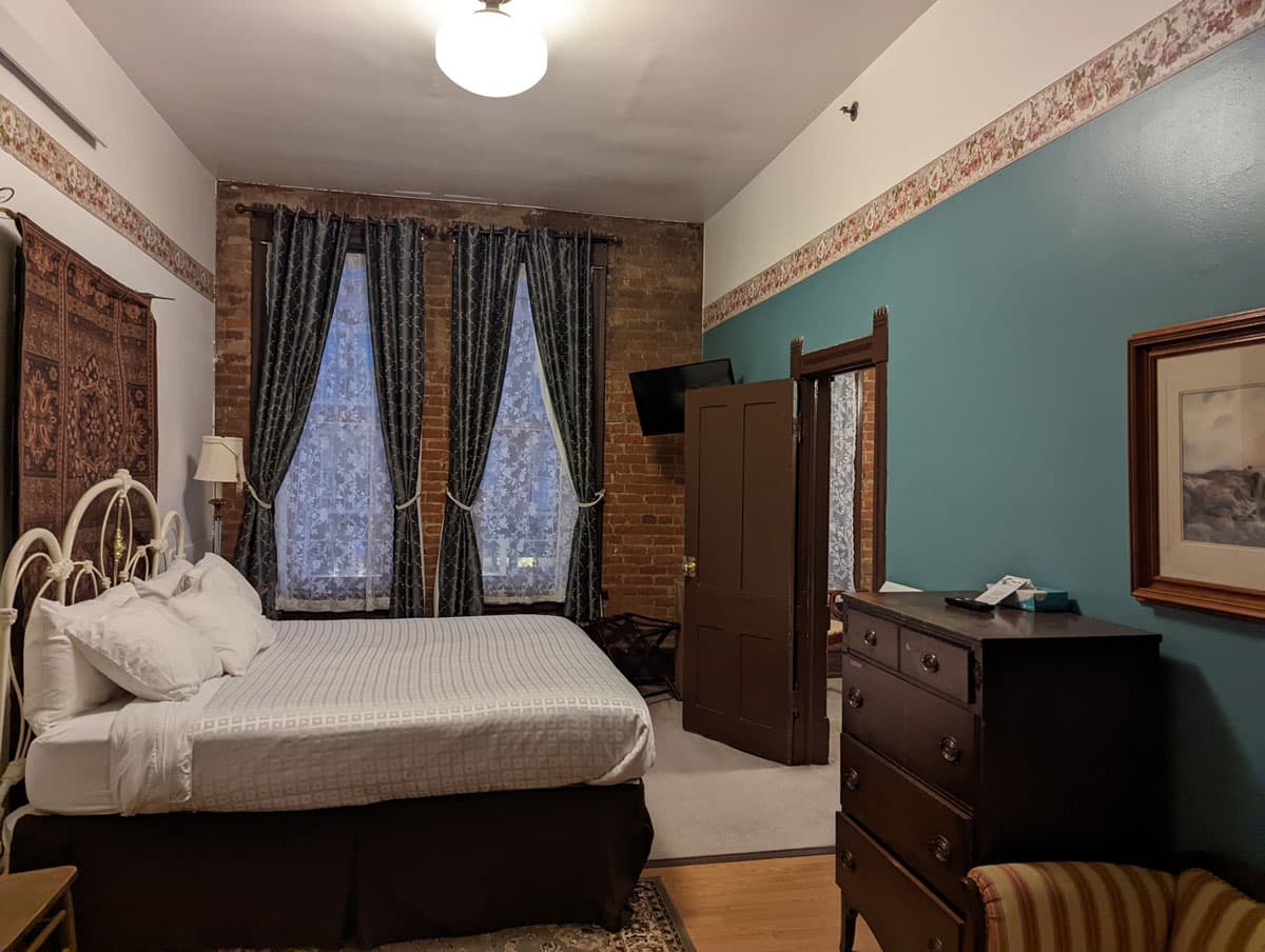 Delaware Hotel room interior with teal-green accent wall, long window drapes and Victorian furnishings