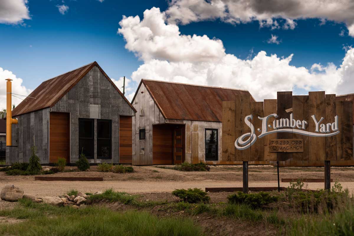 Exterior structures at S.L.umber Yard at FREIGHT in Leadville with blue sky and fluffy white clouds above