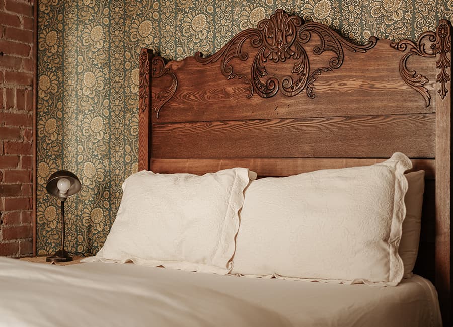 In the Gable House B&B, a soft bed in a room with gilded-gold-accented wallpaper awaits guess in Durango, Colorado.