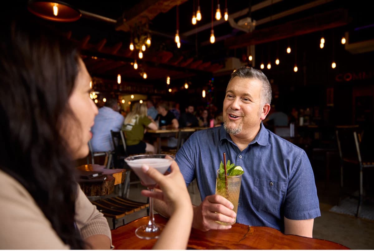 Smiling guests toasting cocktails inside Abbott & Wallace Distillery.