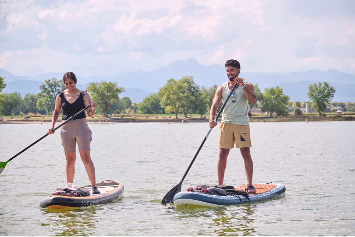 Two people stand-up paddleboarding over calm water.