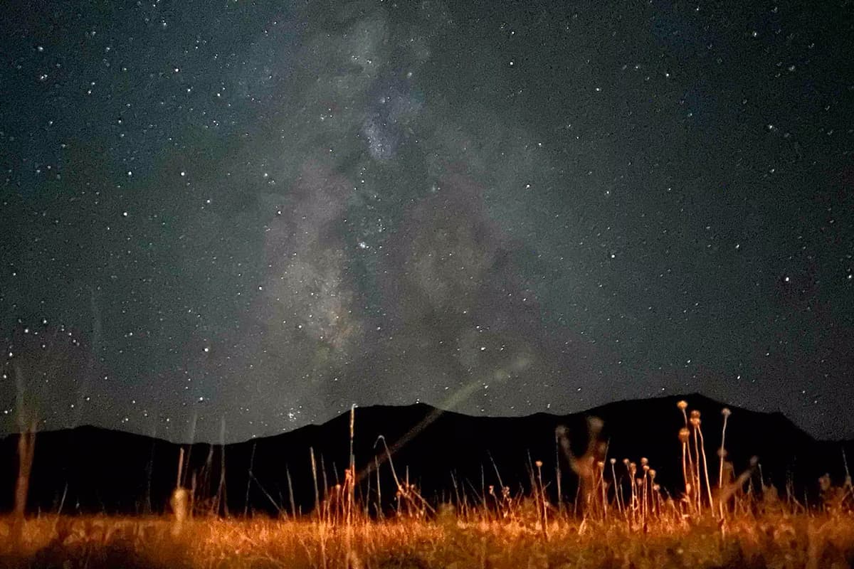 A sky filled with stars and swirls from the Milky Way stretches out over an open meadow near Westcliffe, Colorado.