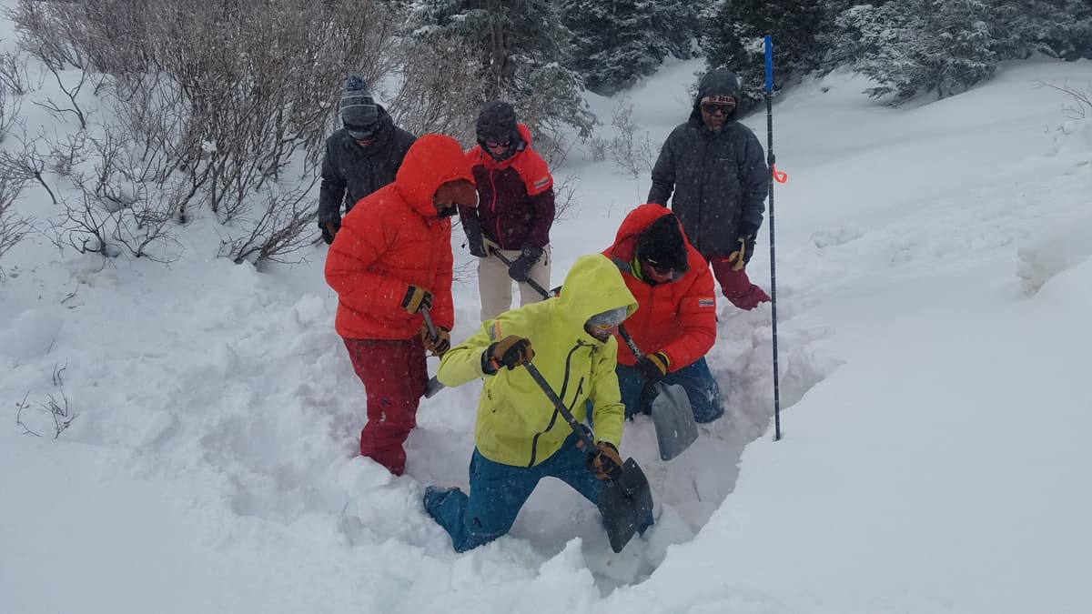 A group examines the snow in an AIARE course about avalanche safety from Colorado Adventure Guides.