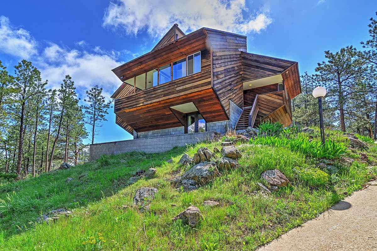 Near Boulder, Colorado, Barret House's striking architecture stands out against the green slope and blue sky.
