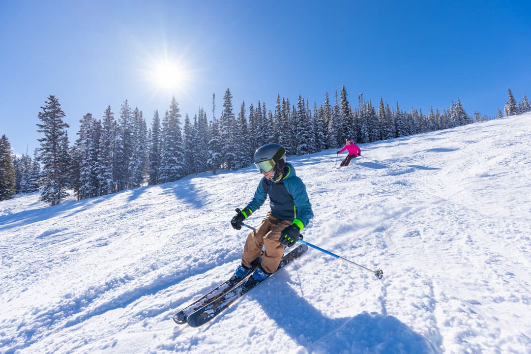 A skier in a helmet safely navigates the snowy slopes under the Colorado sun
