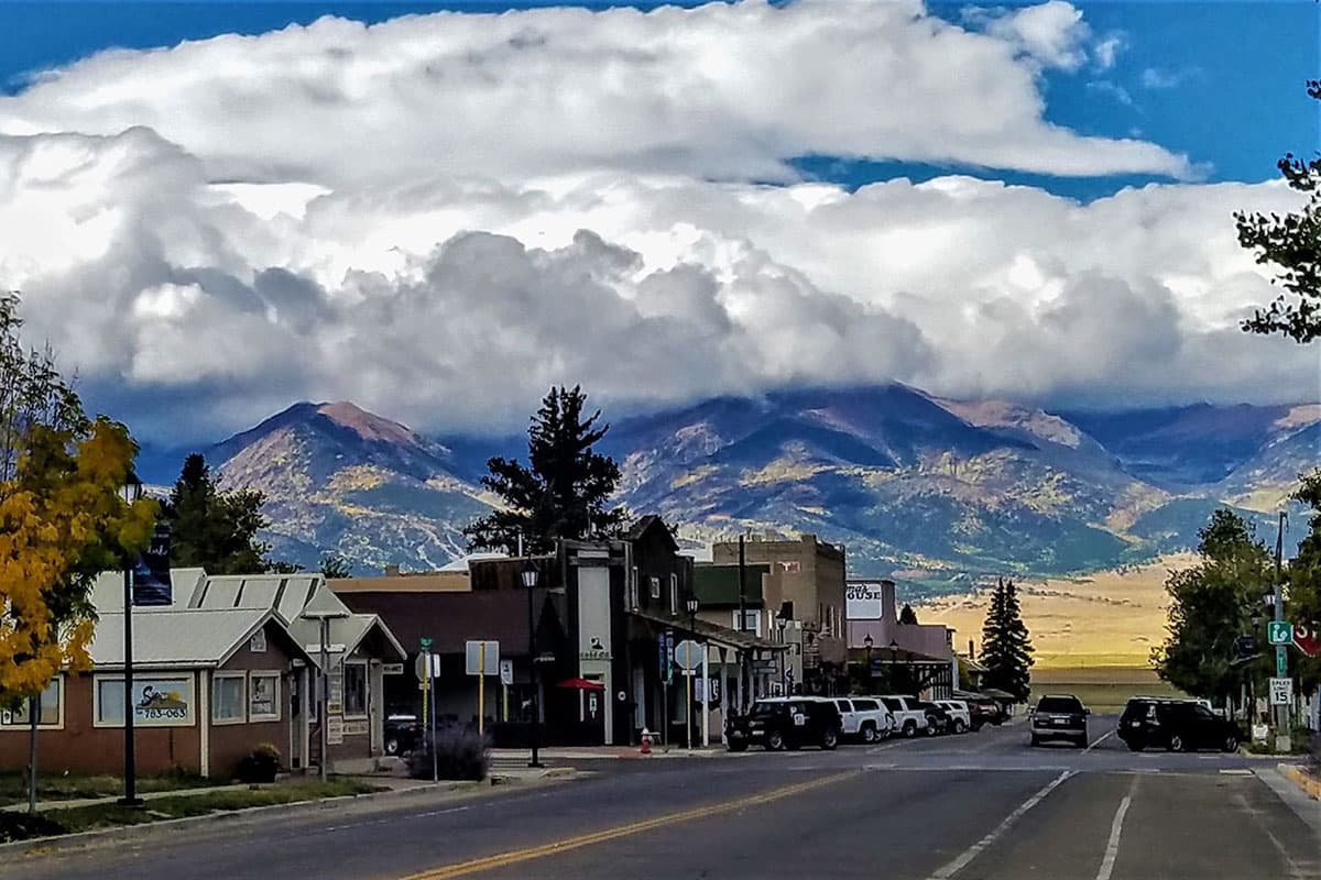 A road travels through the small downtown of Westcliffe, Colorado with the Sangre de Cristo Mountains towering in the background.