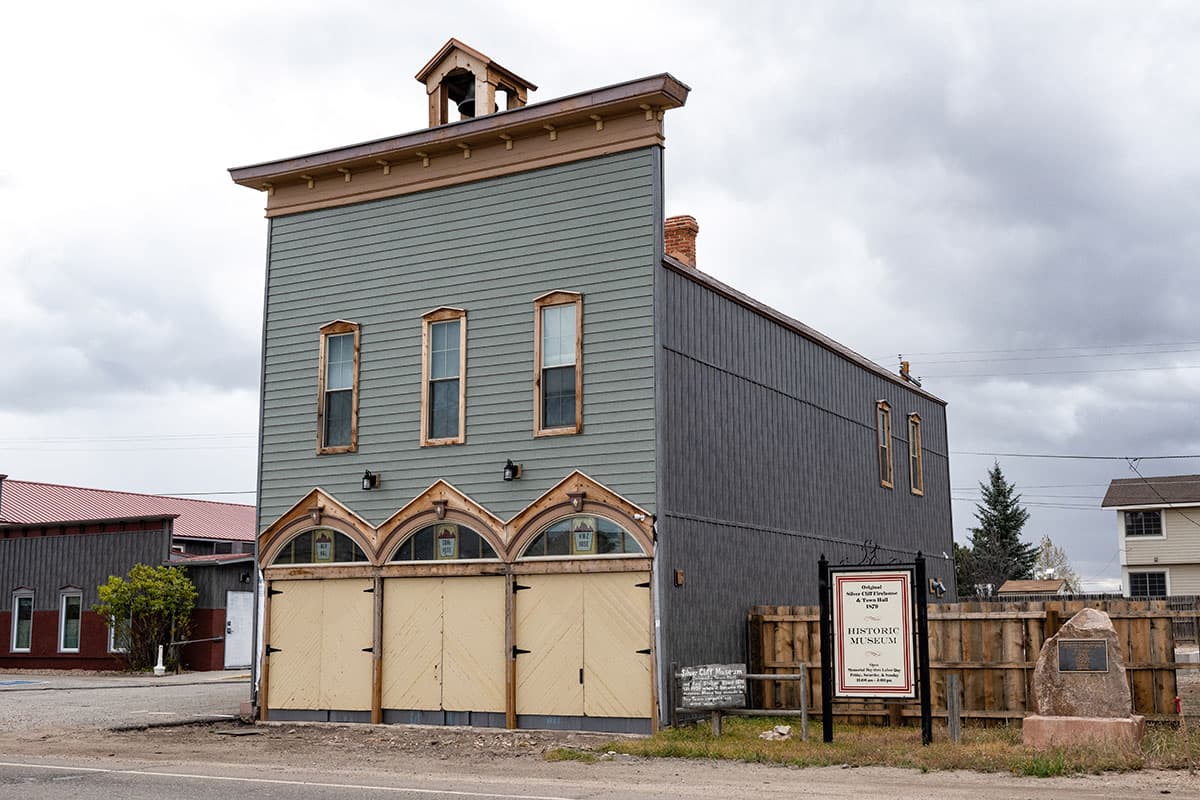 Outside view of a rustic museum building with windows and boarded up doors in Silver Cliff, Colorado.