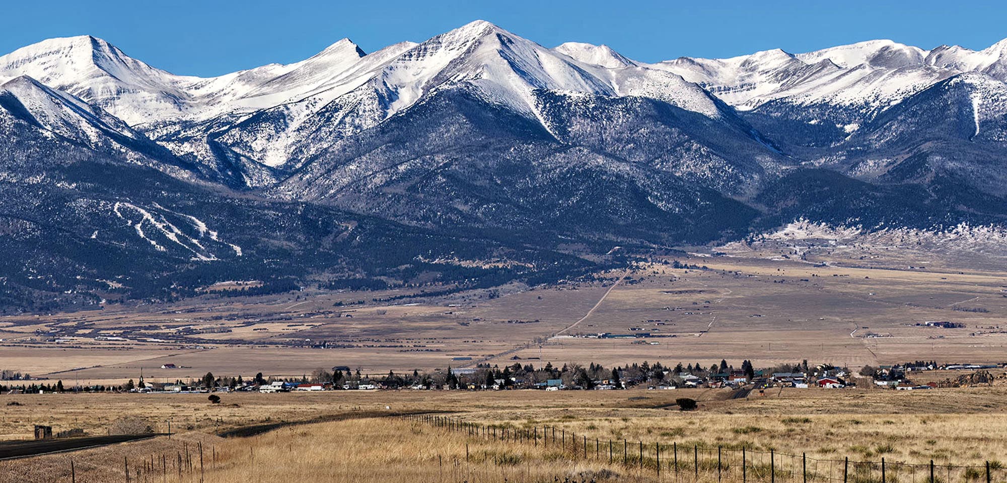 Far away view looking at the town of Silver Cliff with snow-capped mountains in the background, standing tall in Colorado.