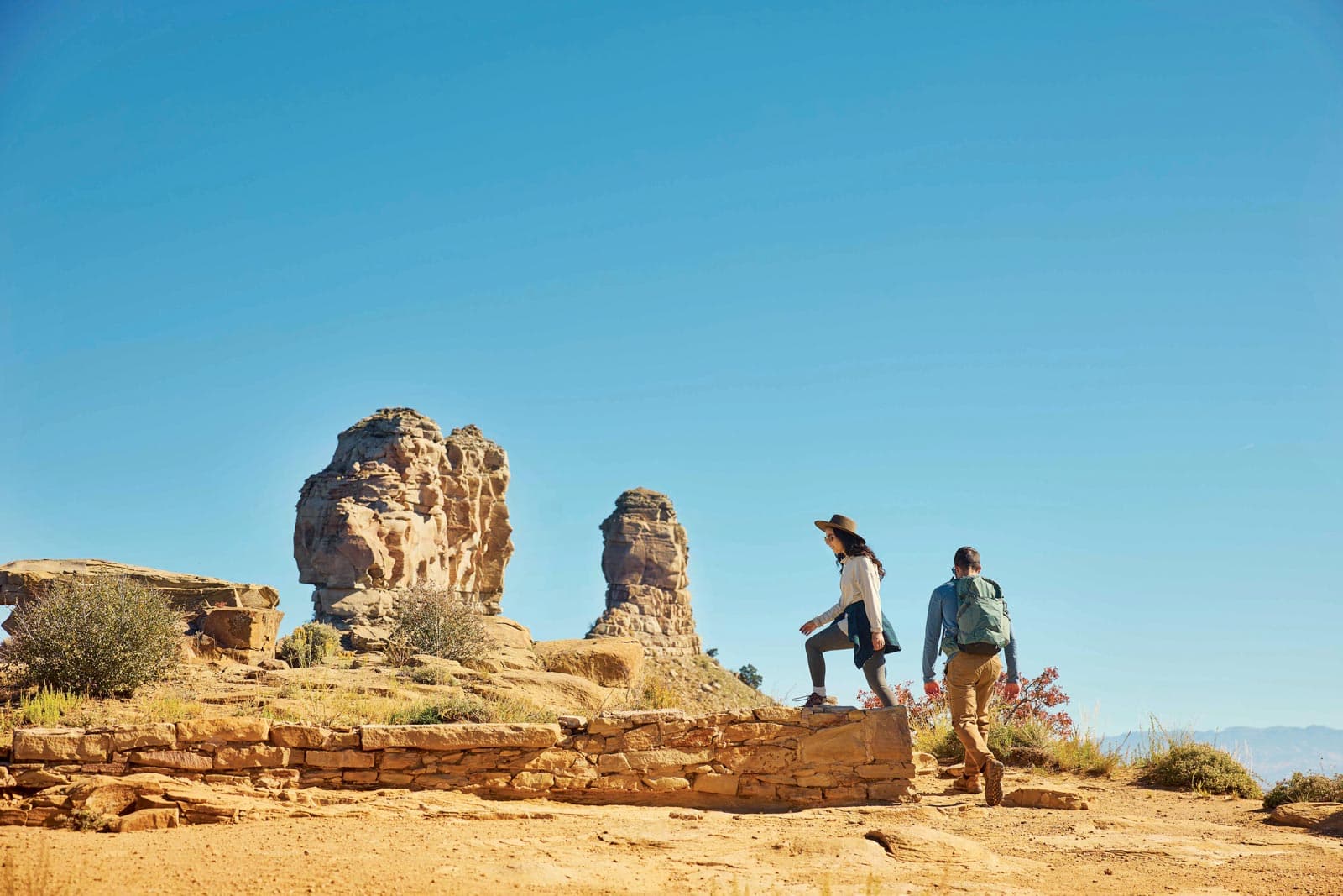 Two people walk near sandstone rock formations in CTO Chimney Rock National Monument
