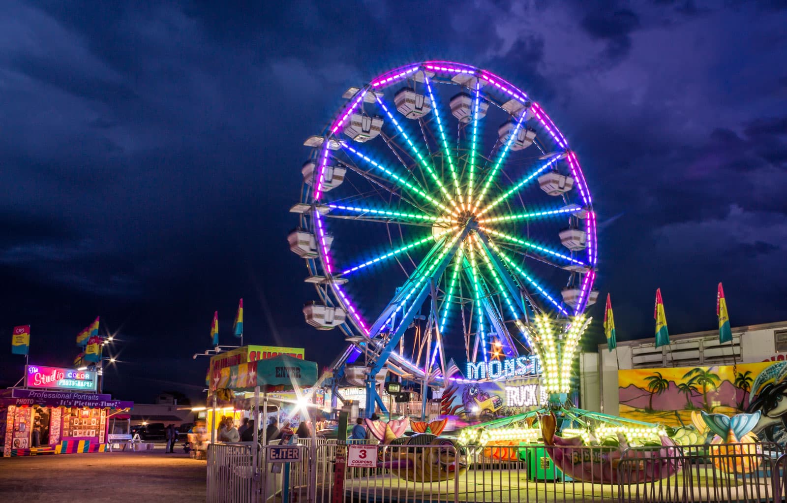 A rainbow Ferris wheel lights up a dark night sky at the Sky Hi Stampede Carnival.