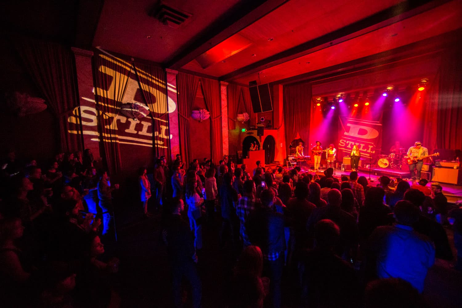 A crowd enjoys a music concert inside a theater