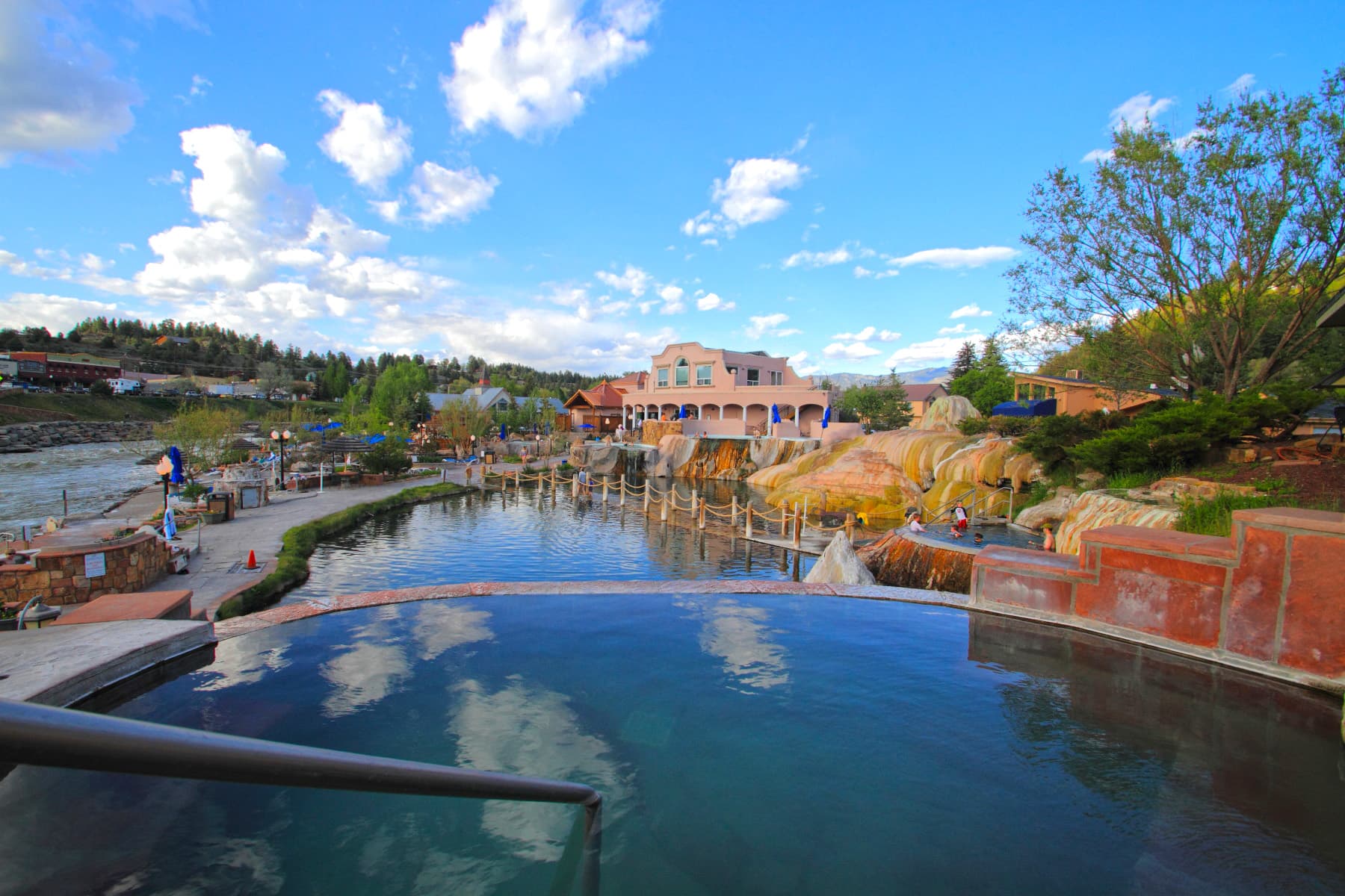 Hot springs pools are surrounding by resort buildings with mountains all around