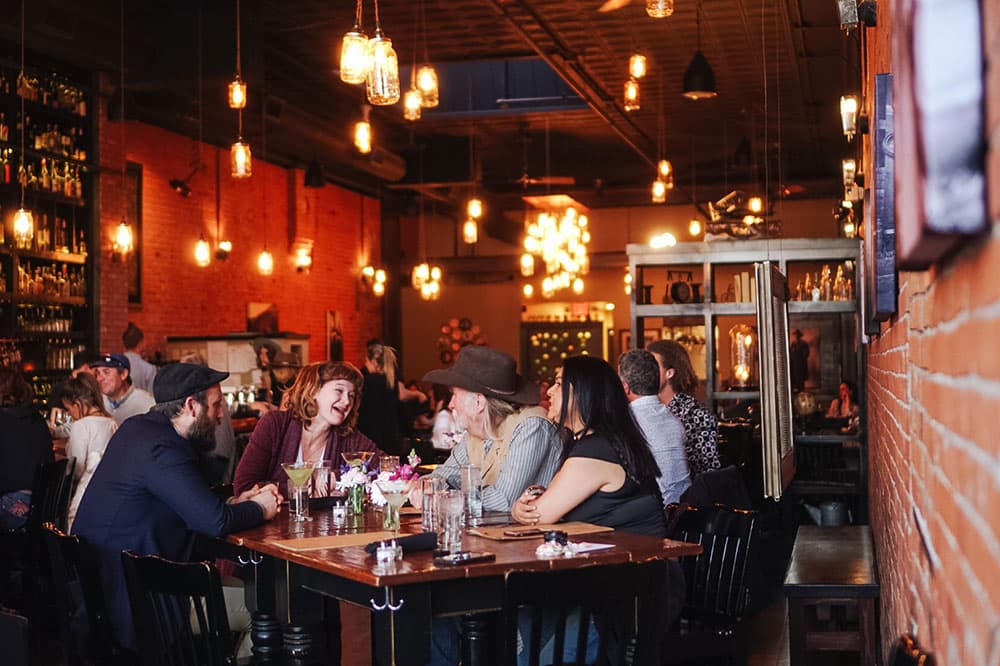 People laugh at a table with ambient lighting at El Moro Spirits and Tavern