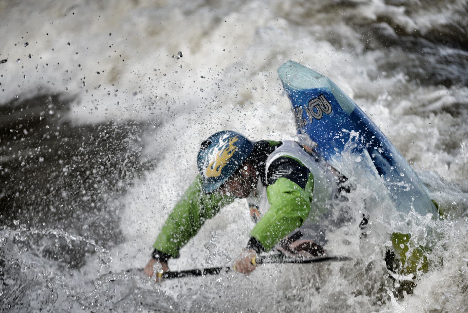 A competitive kayaker wearing a white bid paddles a small, red and green kayak through whitewater rapids near Buena Vista and Salida, Colorado.