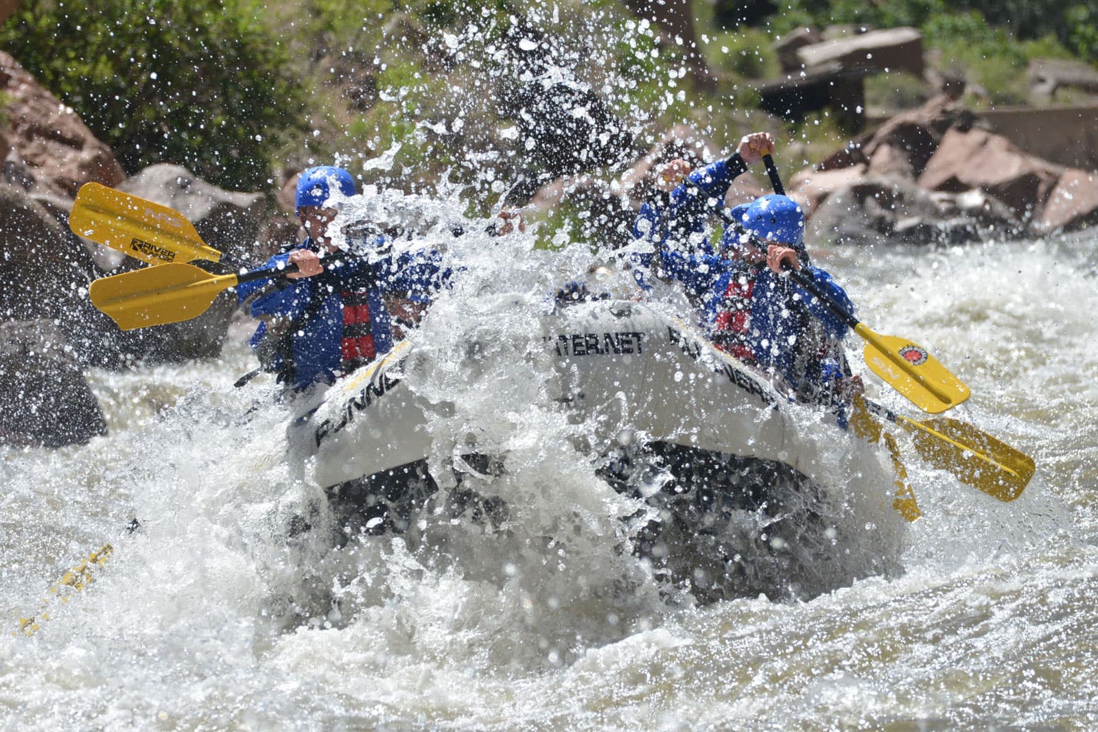 A giant white rapid flies onto a boat full of rafters