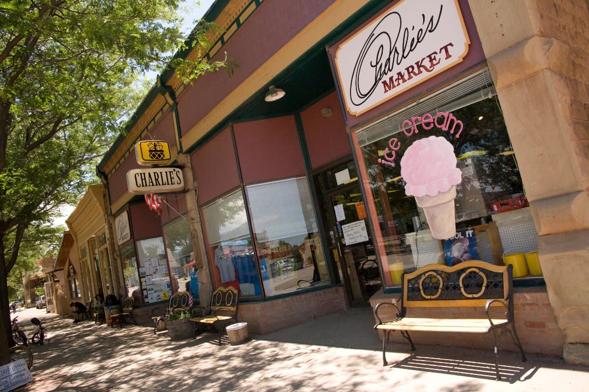 A titled angle of the shops in downtown La Veta. Benches sit in front of a store labeled "Charlie's Market" with an ice cream cone image painted on the glass.