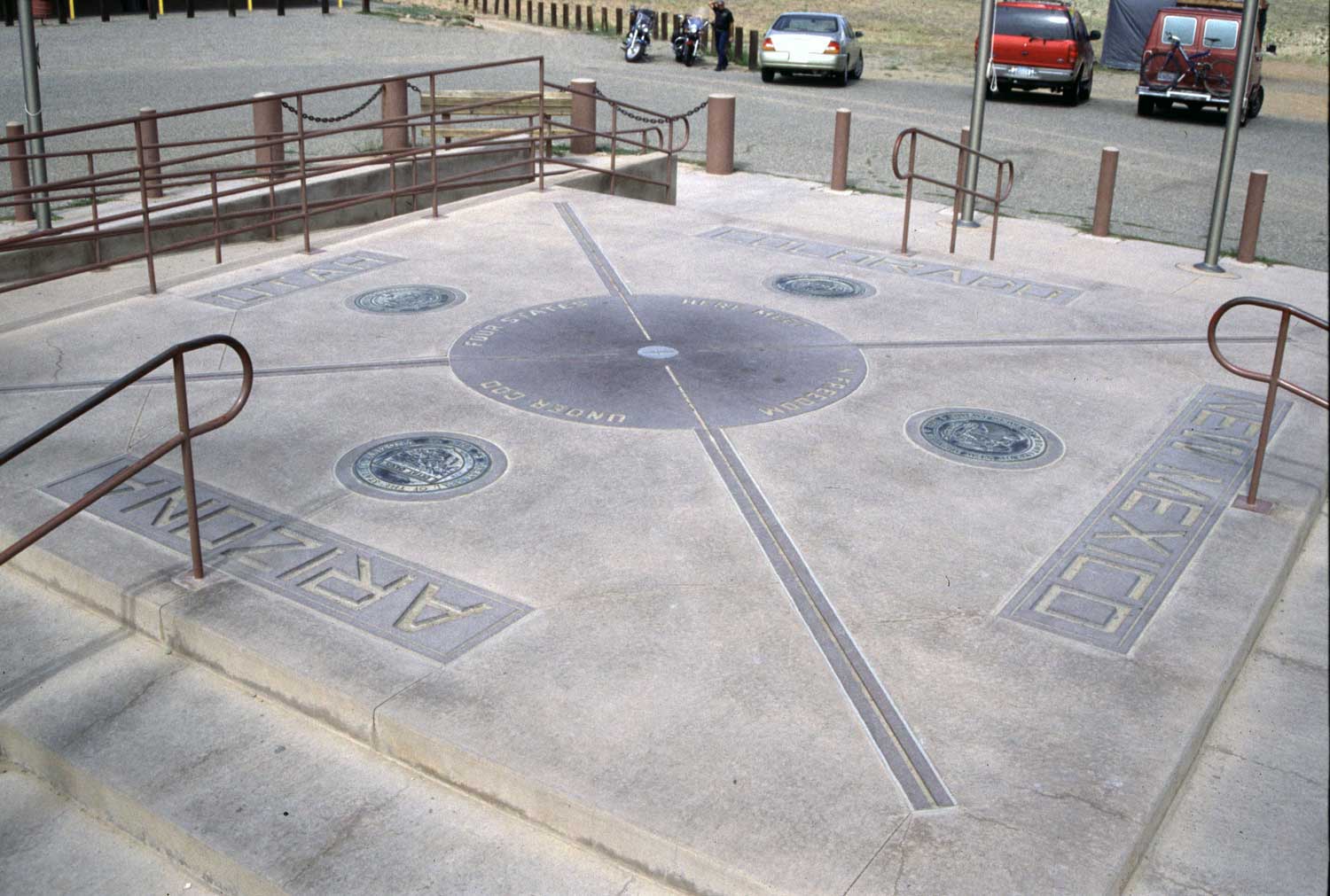 A raised concrete slab engraved with four different state names serves as a landmark known as the Four Corners Monument in Colorado.
