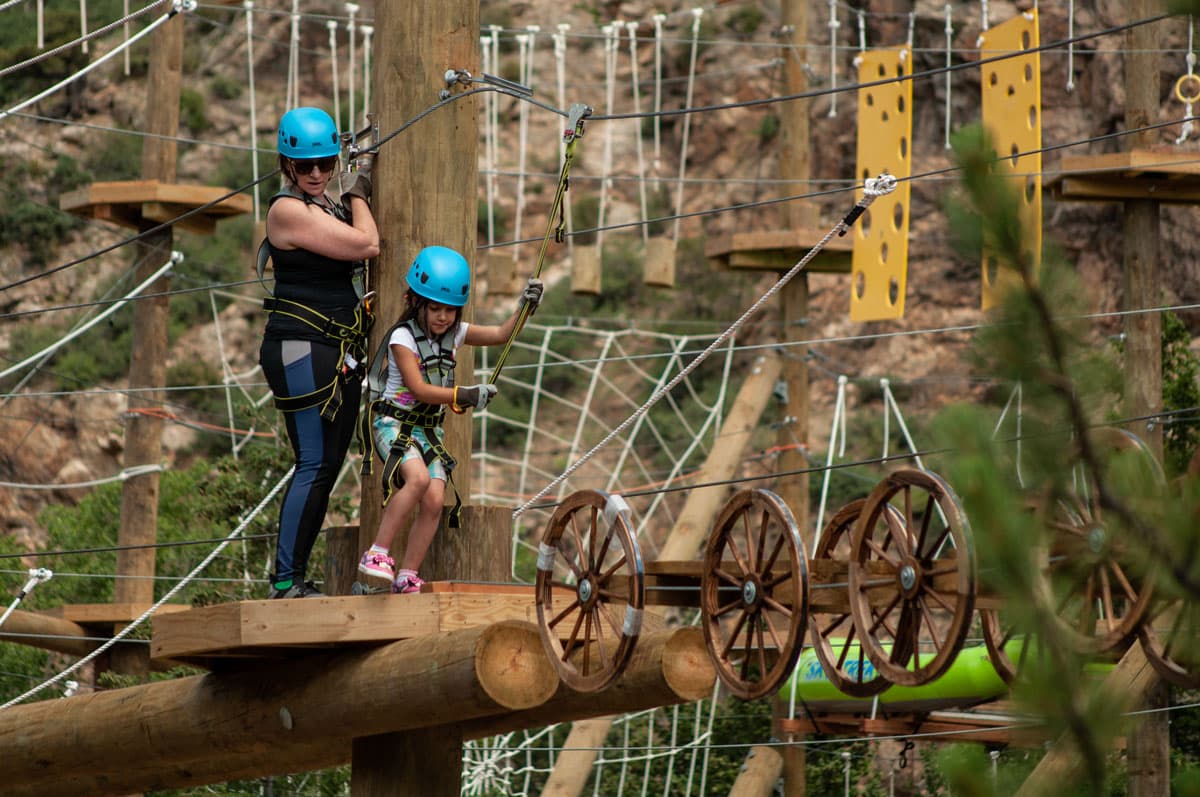 Parent and child get ready to cross a tightrope on the high up obstacle course at Colorado Adventure Center.