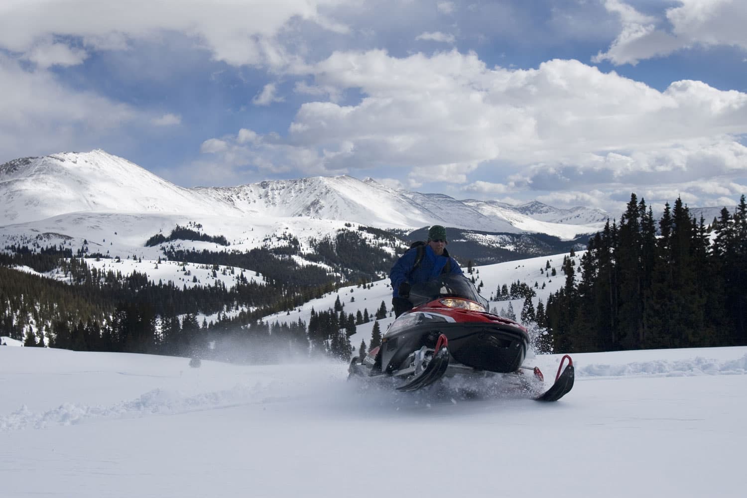 A snowmobile races across a mountain trail