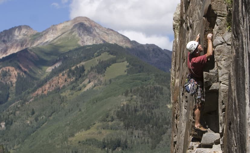A man in a helmet rock climbing in Colorado's San Juan Mountains