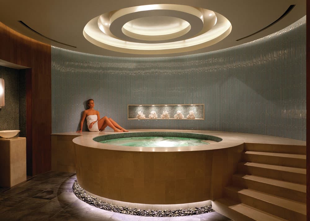 Woman lounging next to a hot tub inside a luxury spa