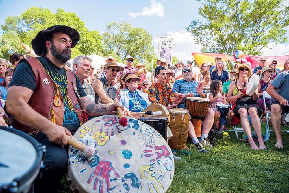 People sit on lawn chairs and play a variety of drums, from bongos and to hand drums at the Carbondale Mountain Fair in Denver.