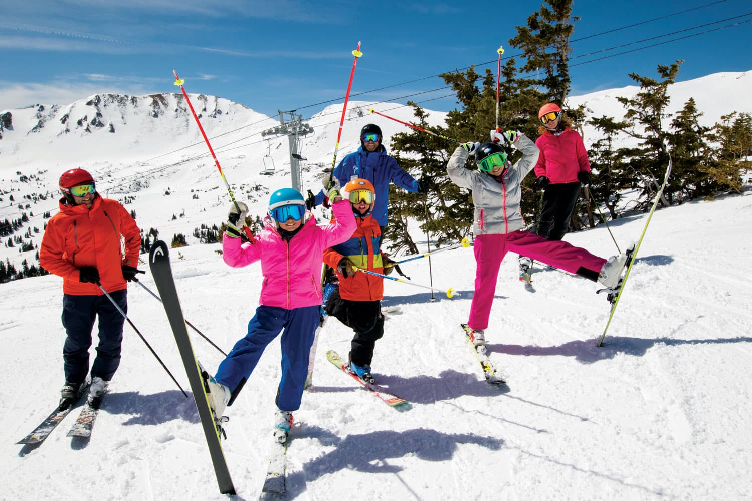 Skiers jump in the air with snow mountains all around them