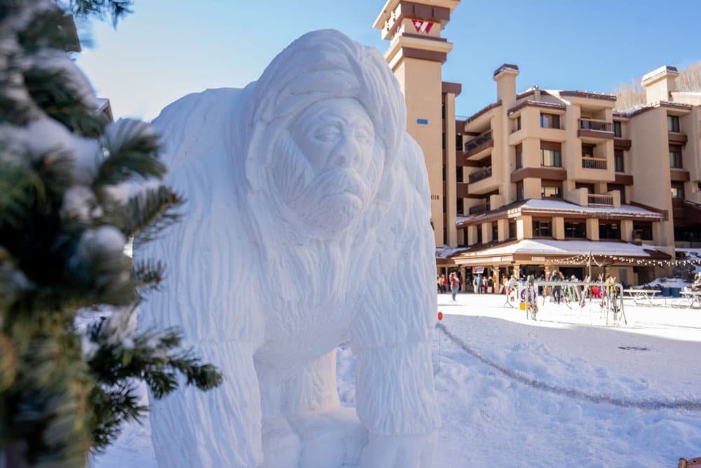 A snow sculpture with a winter resort in the background