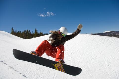 Snowboarder in bright pants gliding over snow-packed terrain in Colorado.