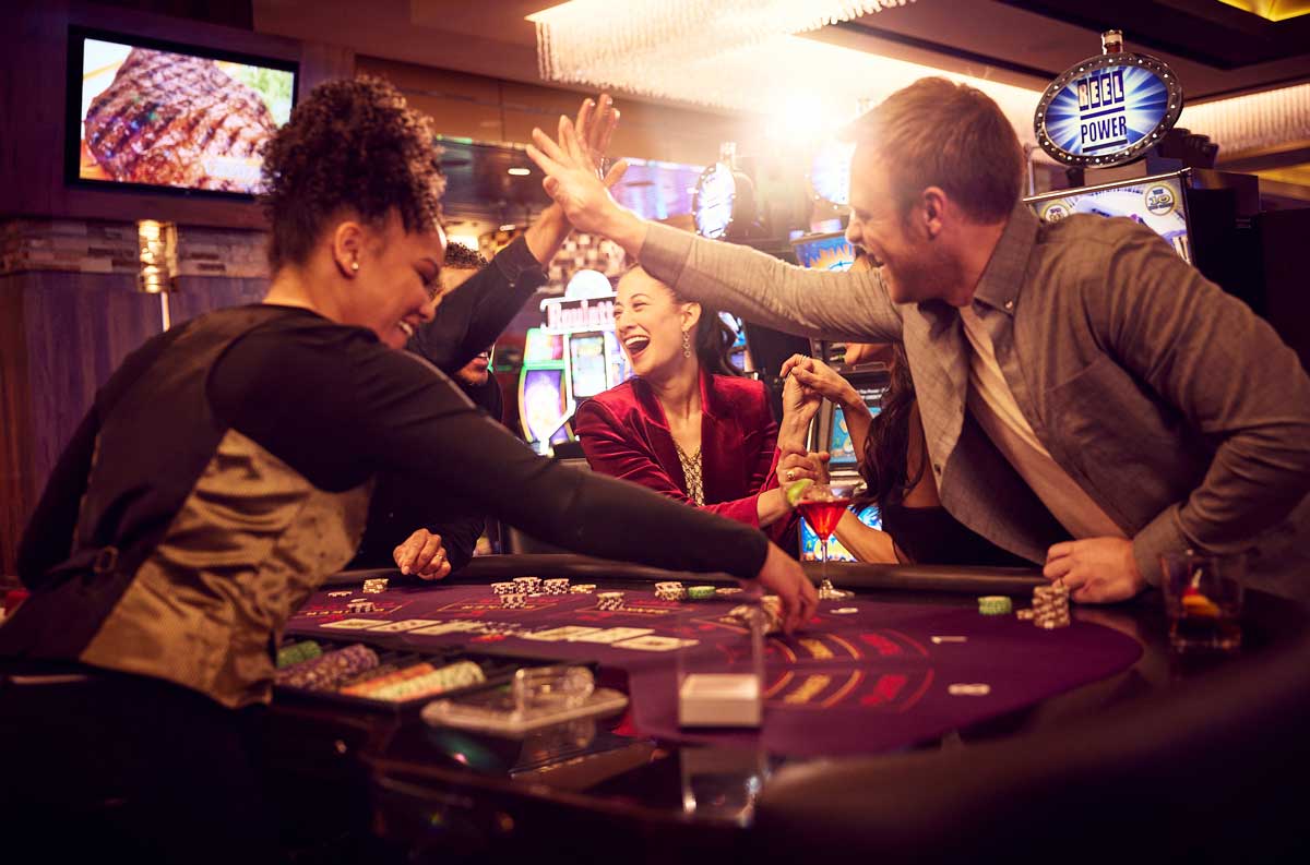 A group smiles and high fives over a table as they play baccarat at the Monarch Casino Resort Spa Black Hawk