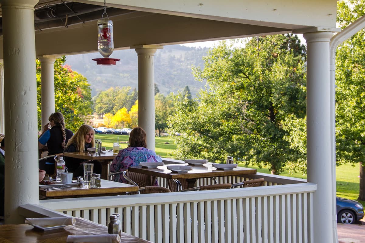 Summer morning at Chautauqua Dining Hall on the porch with people eating.