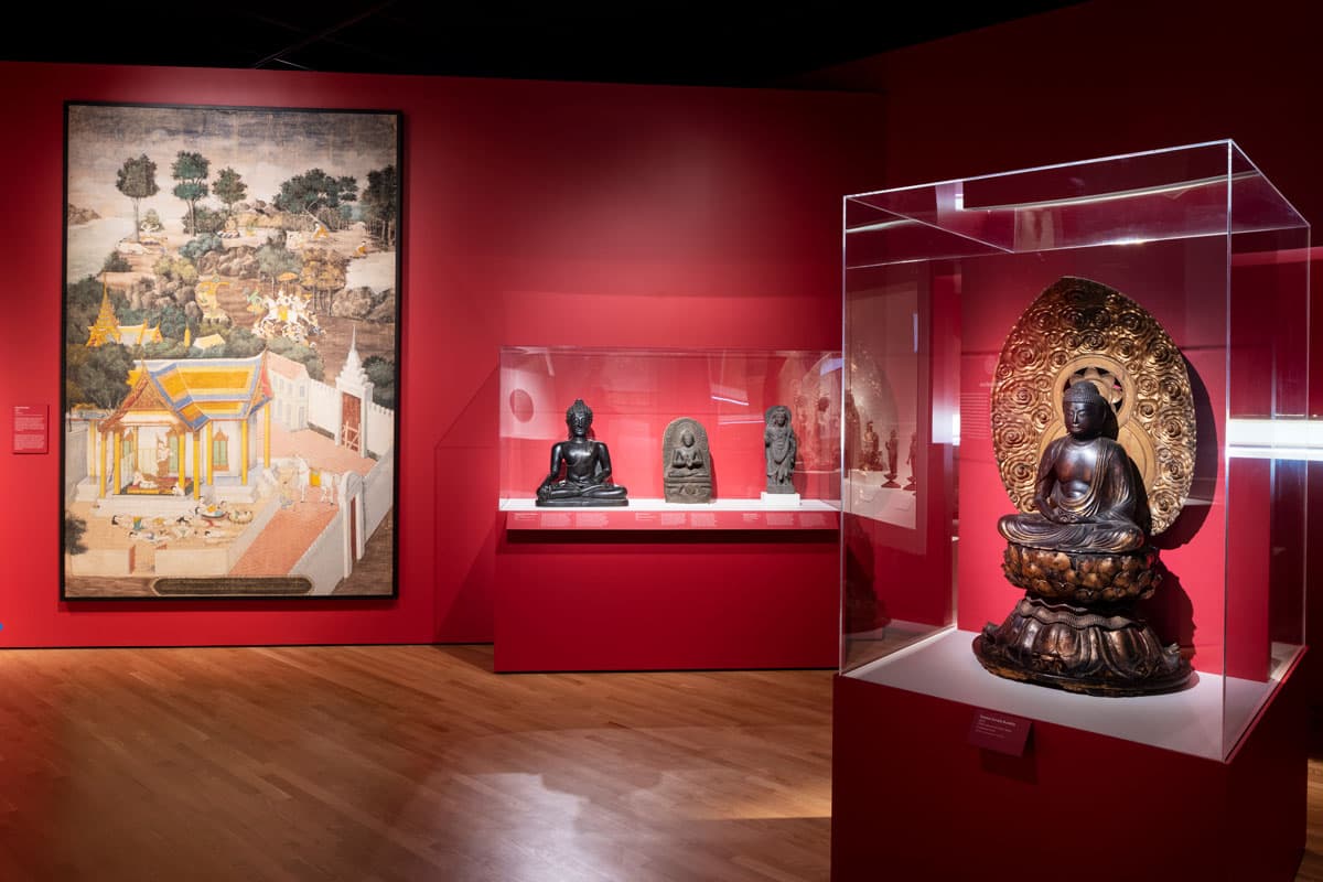 Paintings and statues are displayed against dark-red walls, part of Denver Art Museum's Asian Art Collection, live on the fifth floor of the museum in Colorado.