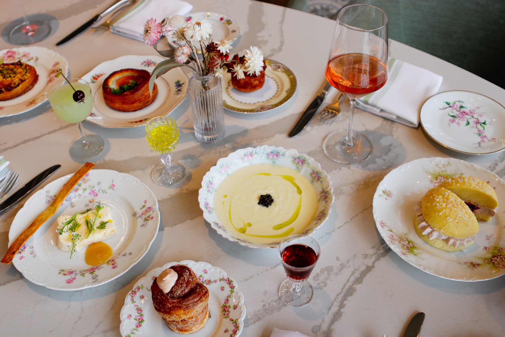 A table with several delicate dishes, bowls and saucers filled with various pastries