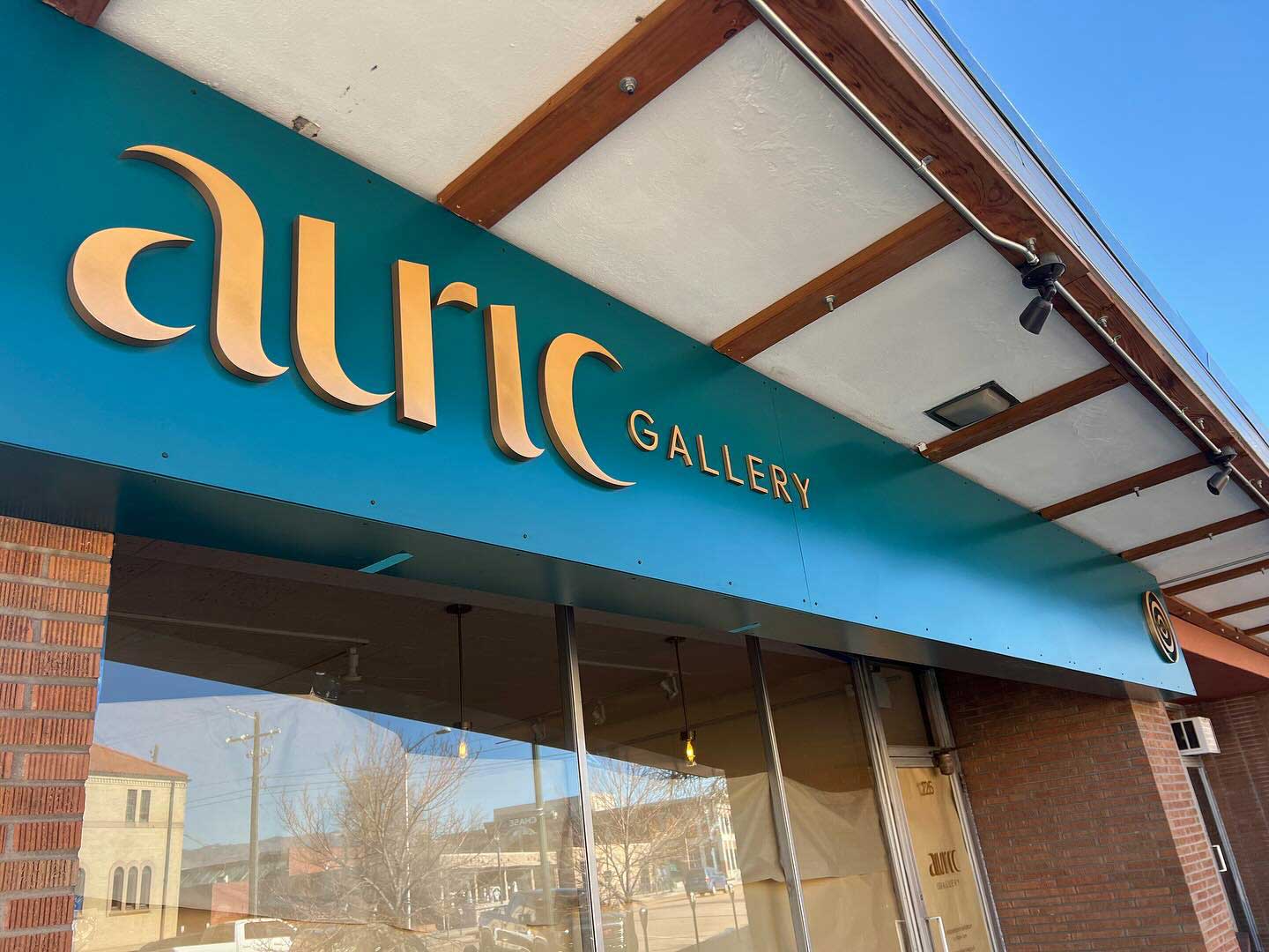 The exterior of Auric Gallery, yellow text on a green background