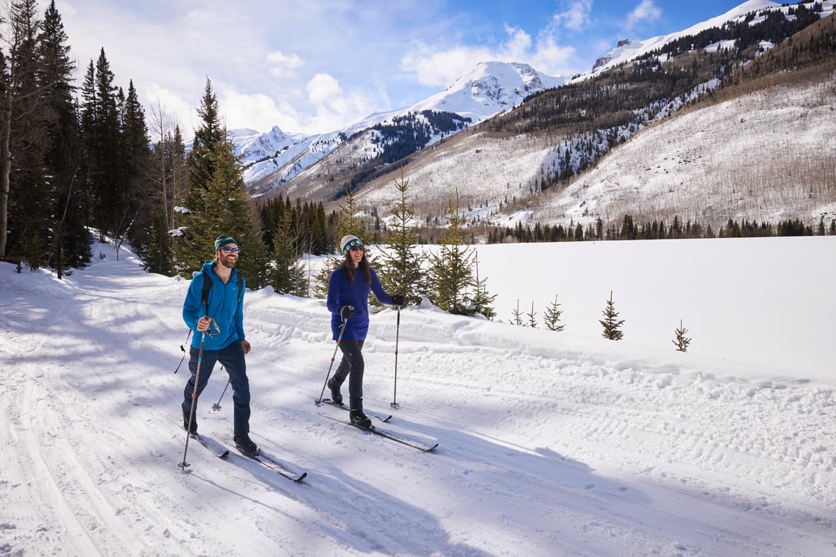 Two people cross-country ski on a groomed trail in Ouray, Colorado