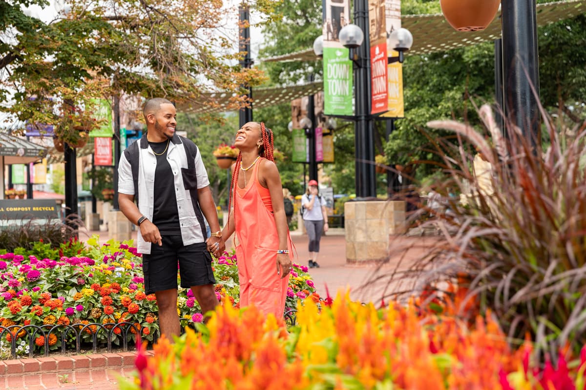 A couple holds hands and laughs as the stroll past the shops of Boulder's Pearl Street