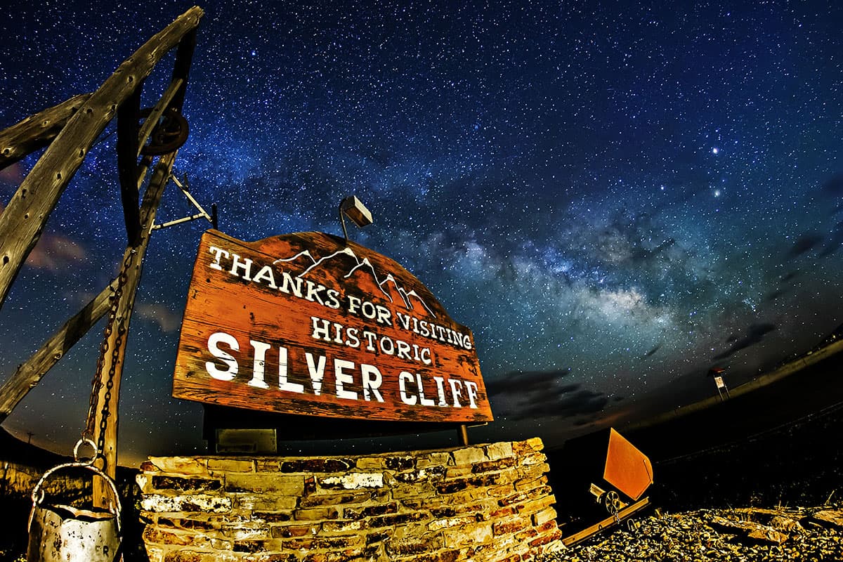 A rustic sign reading "Thanks for visiting historic Silver Cliff" at night with stars shining bright high above.