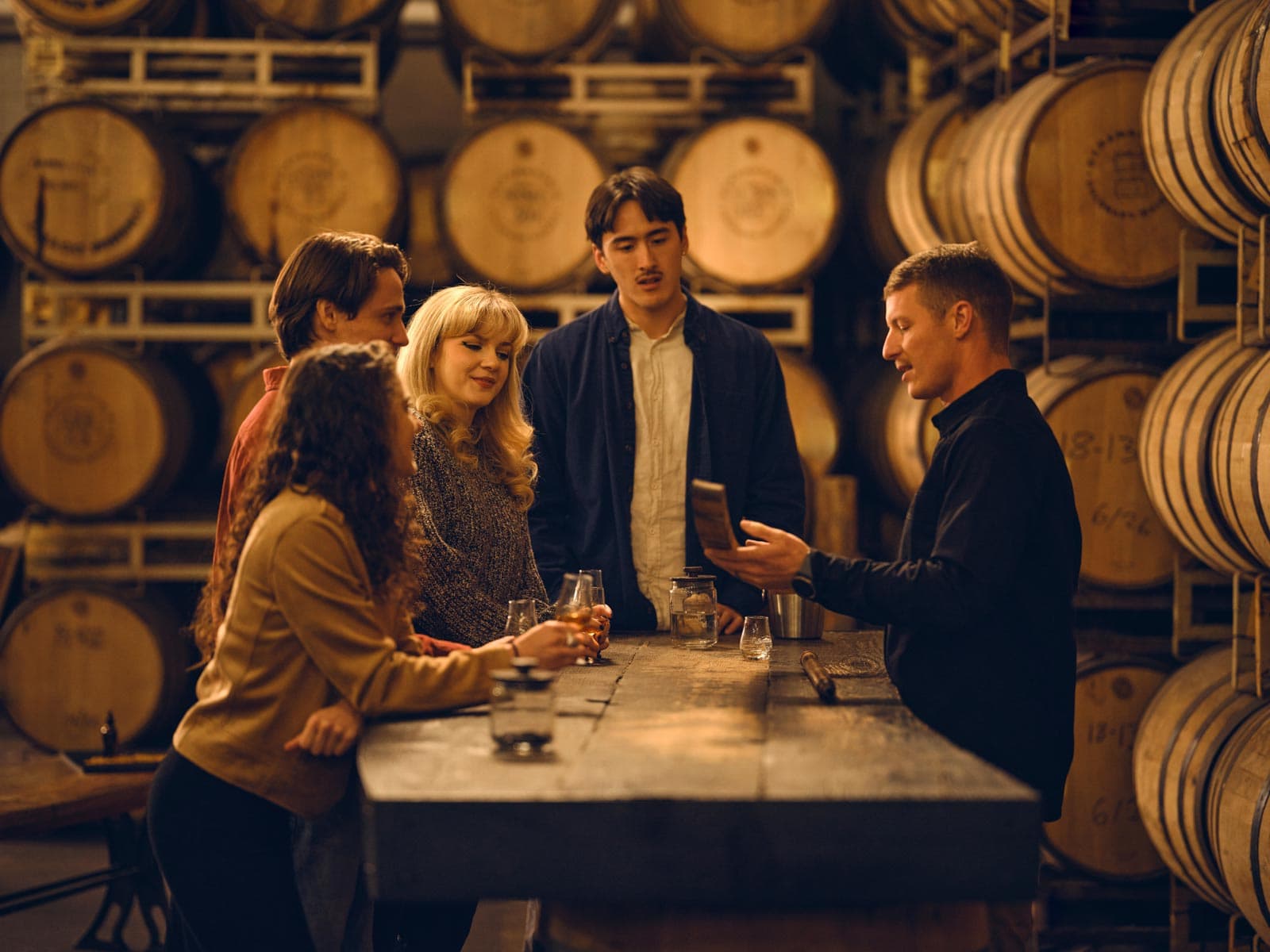 Four people stand around a bunch of casks at a Colorado distillery