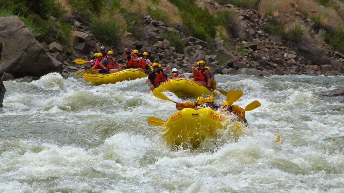 Three groups of adventurers in yellow rafts make their way through thrilling whitewater rapids near Colorado Springs, Colorado.