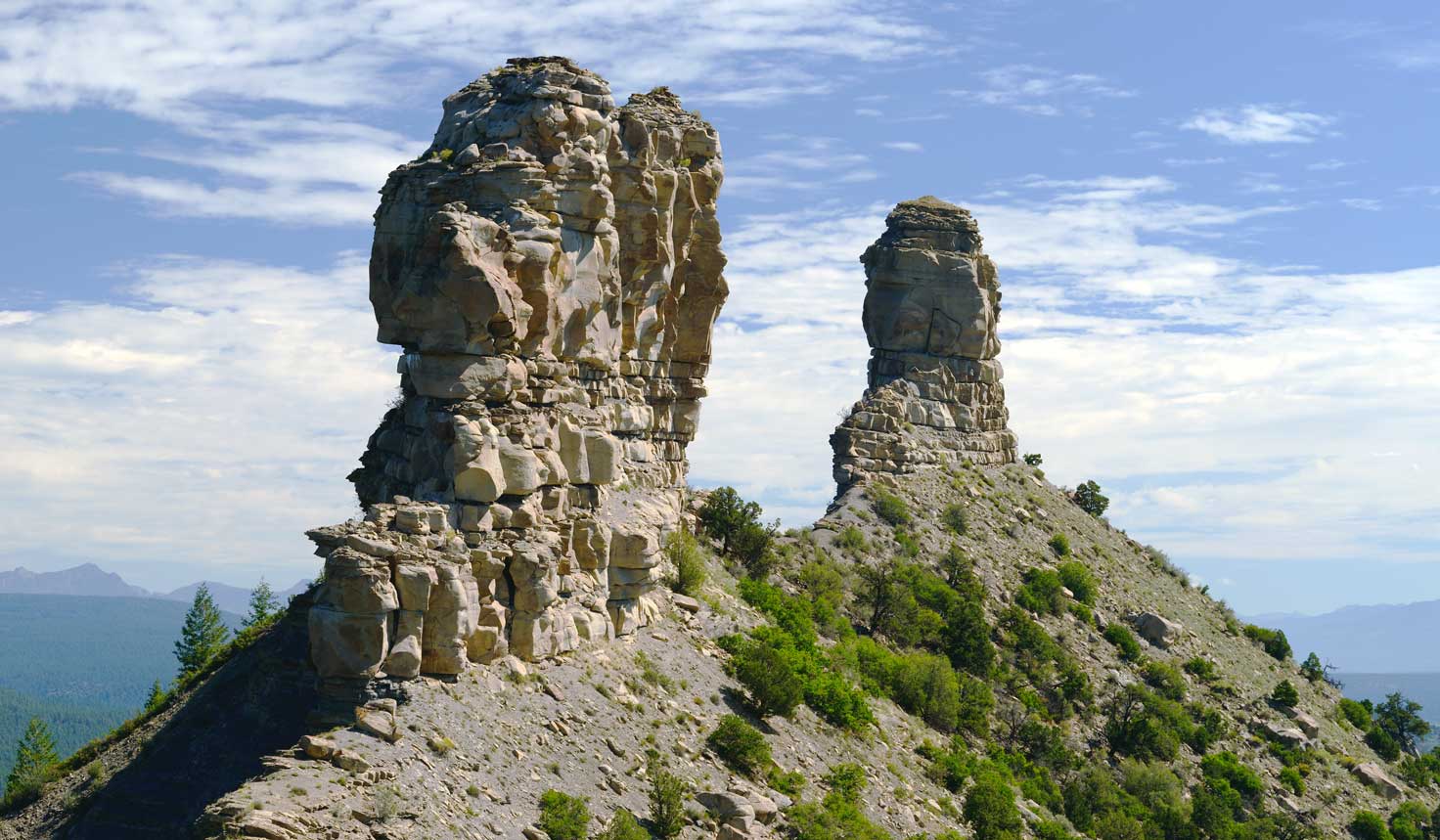 Two towering pinnacles of gray rock defy gravity's pull at Chimney Rock National Monument.