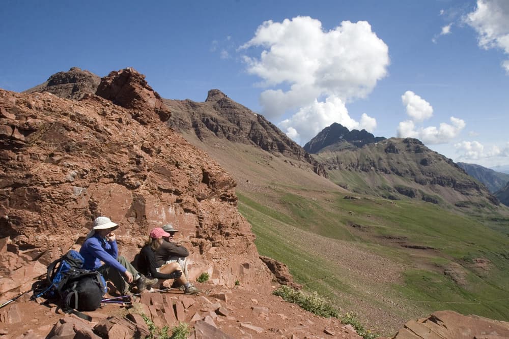 Two backpackers rest on a red-rock trail that leads to the summit of peak