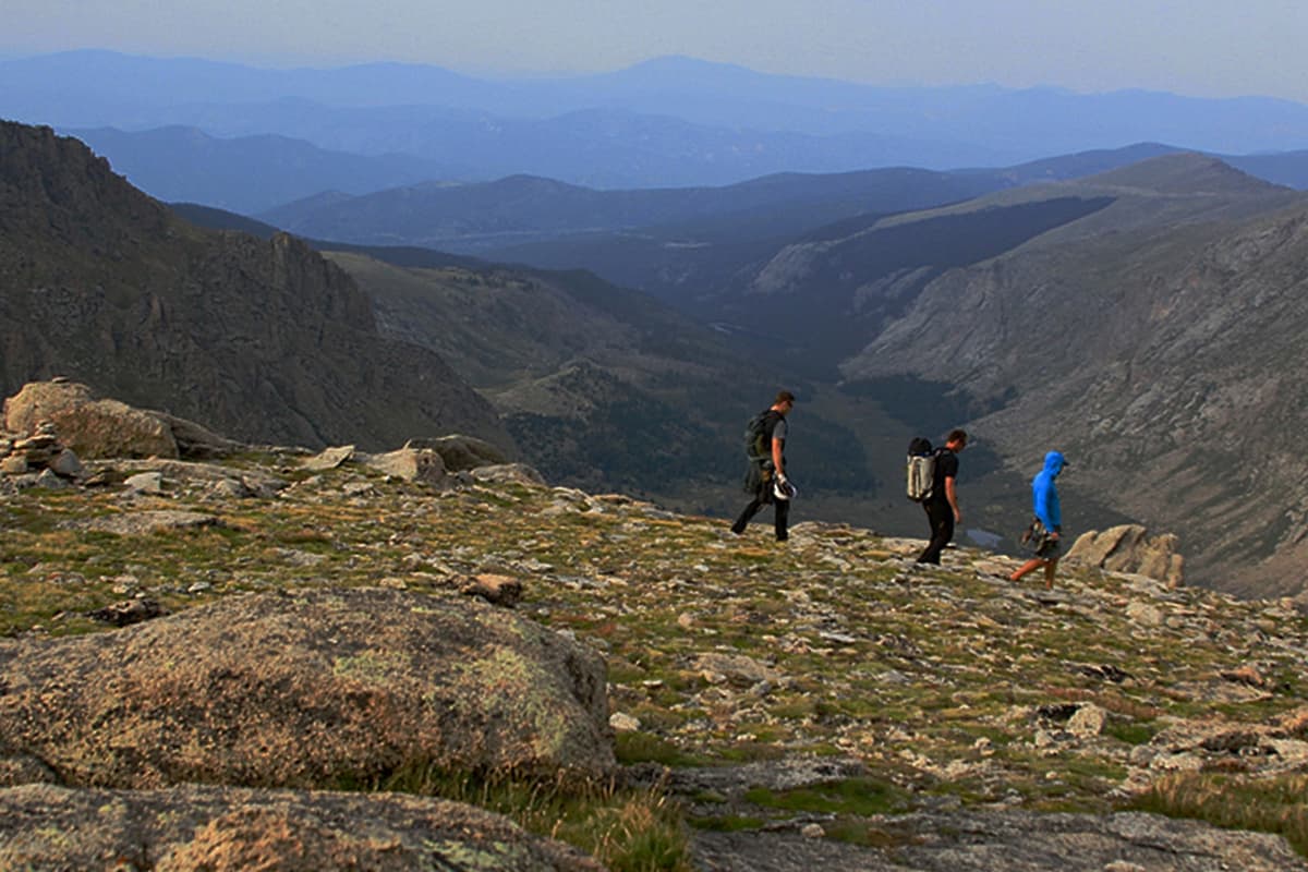 People hiking across a high mountain ridge in front of soaring mountains inClear Creek County