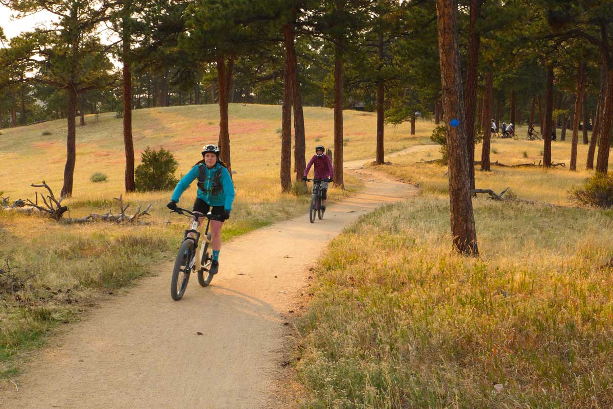 Two people mountain biking on a clean path on a sunny day at Betasso Preserve
