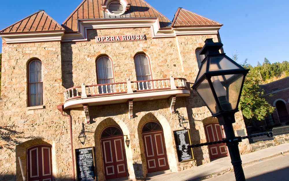 A sandstone building with arched doorways and windows houses the historic Central City Opera House in Central City, Colorado.