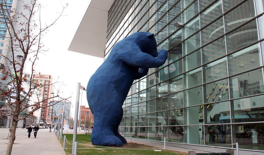 A giant sculpture of a 2-story blue bear peers in a convention center's windows in Denver, Colorado.