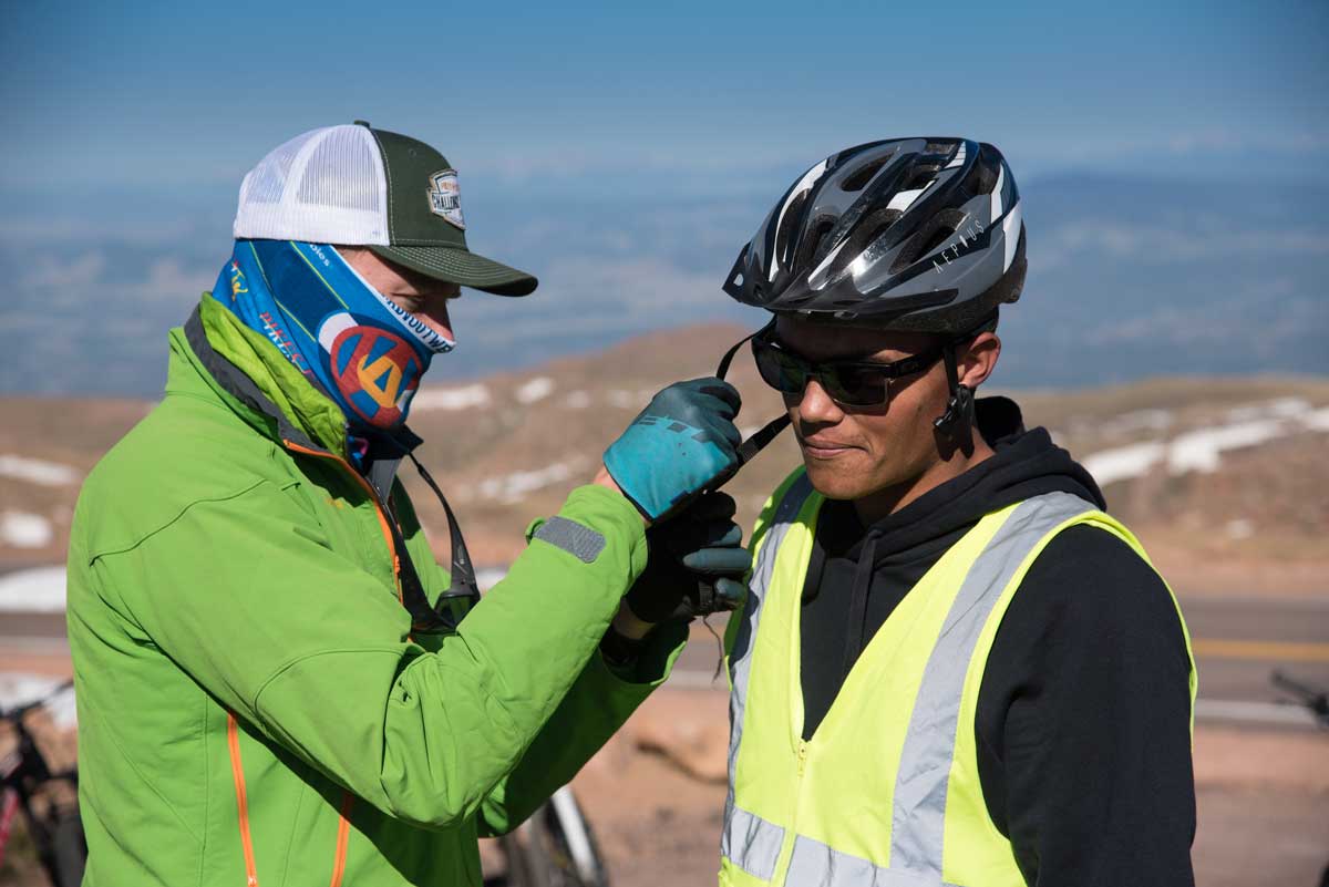 A guide adjusts the fit of a biker's helmet