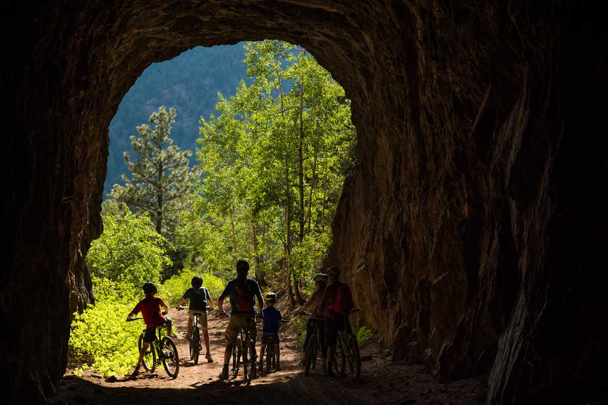 A family of bikers wait at the entrance of a granite tunnel