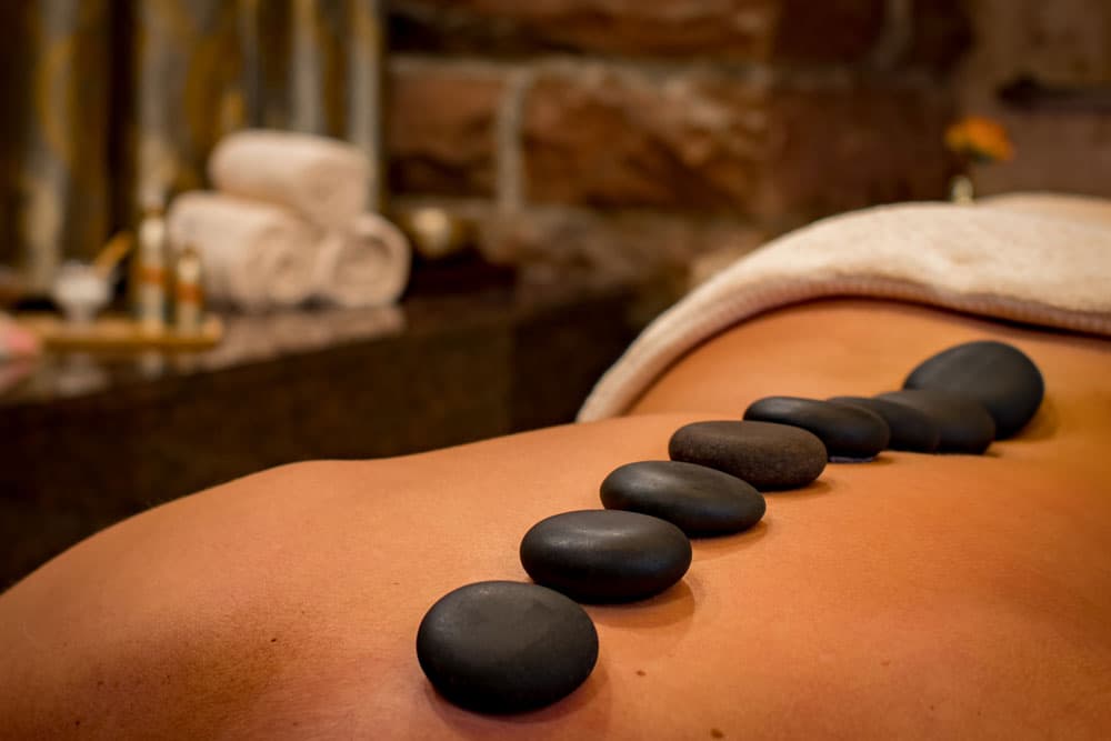 A line of hot rocks rest on a person's back at Spaaah in Durango
