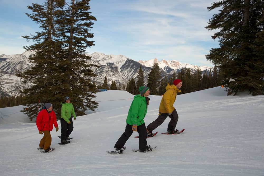 A group of children snowshoeing with snowy mountains in the background