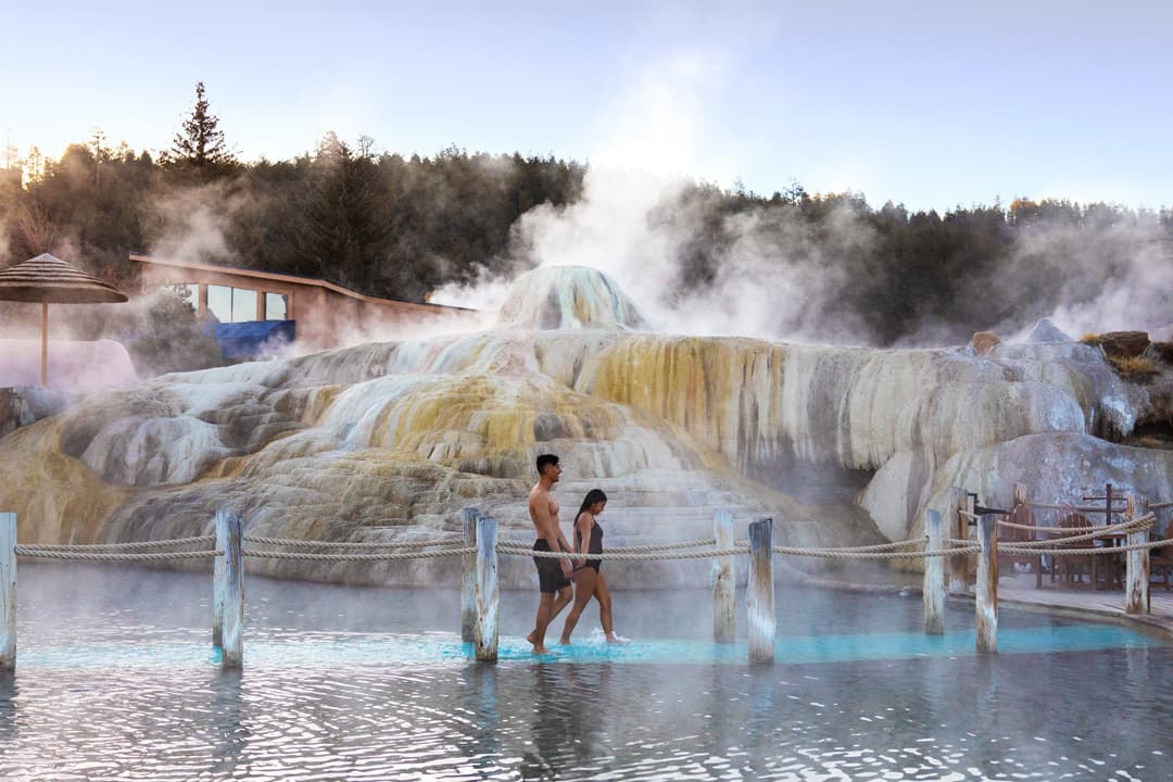 Two people walking past natural hot springs in Pagosa Springs in winter